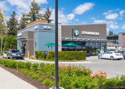 Exterior view of a Starbucks retail building at Belmont Market with landscaped surroundings.
