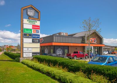 Belmont Market shopping centre entrance sign with retail stores and parking area.