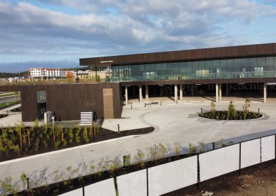 Modern architectural exterior with concrete columns and landscaped gathering spaces at the Beachlands development.